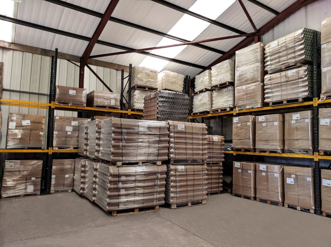 Warehouse interior with stacked pallets of packaged paper tubes and shelves filled with boxes in Cliffe Common, Yorkshire.