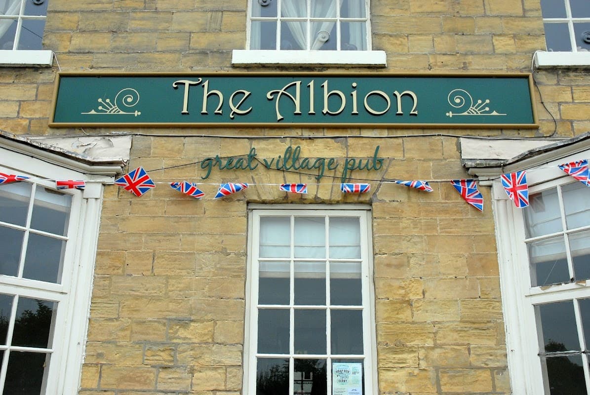 The Albion restaurant sign with Union Jack bunting and large windows on a stone building in Clifford, Yorkshire.