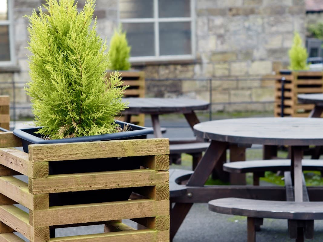 Potted greenery in wooden planters beside picnic tables at Blacksmith's Arms Inn in Cloughton, North Yorkshire.
