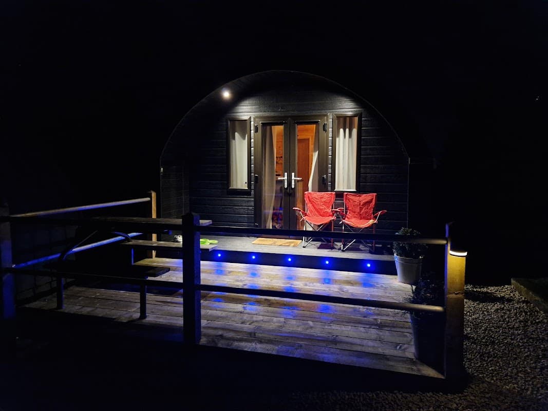 Cozy entrance of The Bryherstones Country Inn with two red chairs and blue lights illuminating the wooden deck at night.