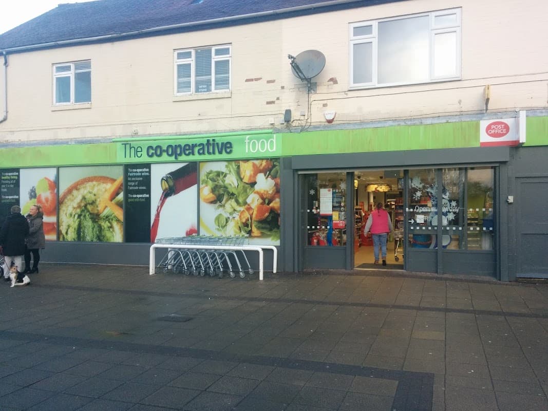 Co-op Food shop exterior with green signage, shopping carts outside, and colorful food images on the windows.