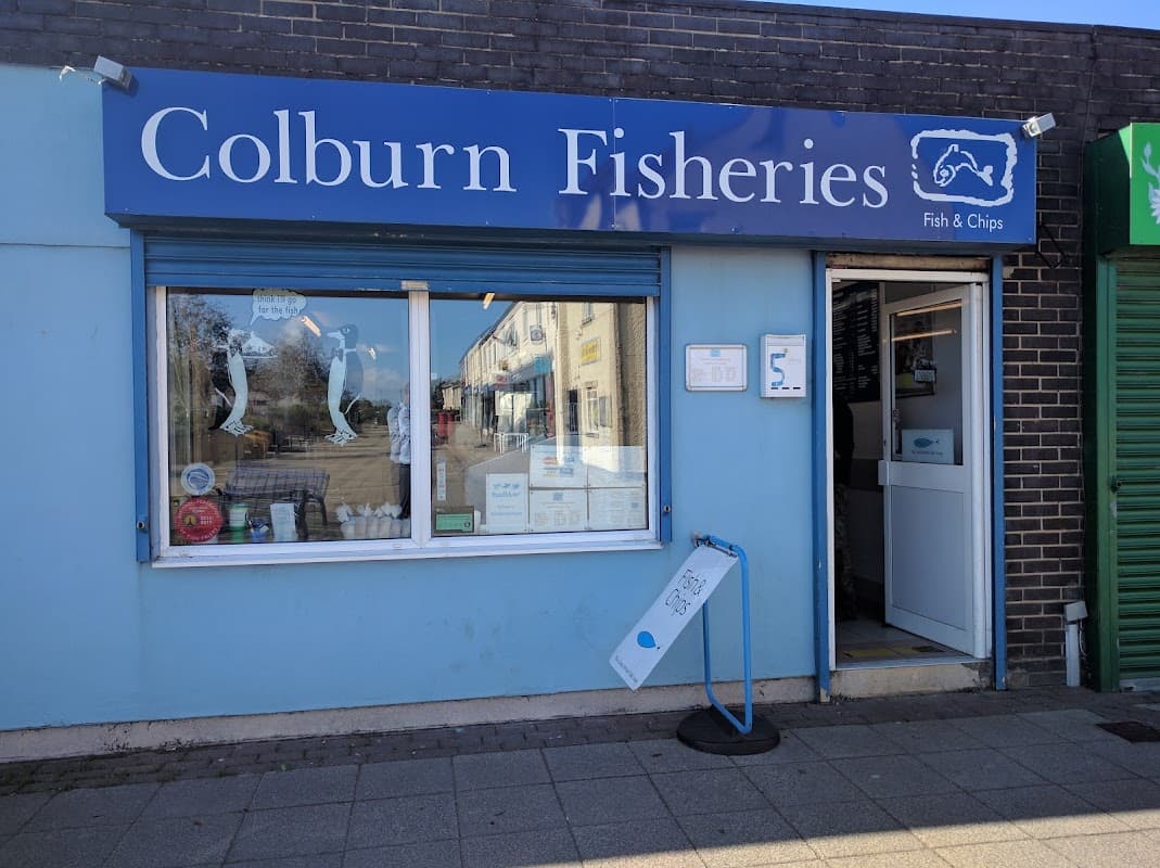 Blue storefront of Colburn Fisheries with a sign for fish and chips, menu displayed, and a welcoming entrance.