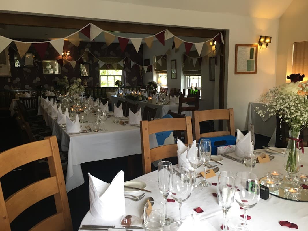 A cozy bar with tables set for dining, adorned with bunting and flowers, creating a festive atmosphere.