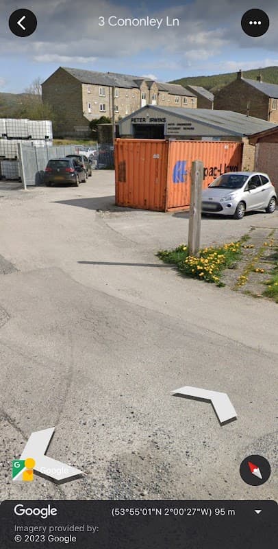 Business premises with a shipping container, parked cars, and a sign for "Peter Irwins" in a rural setting.