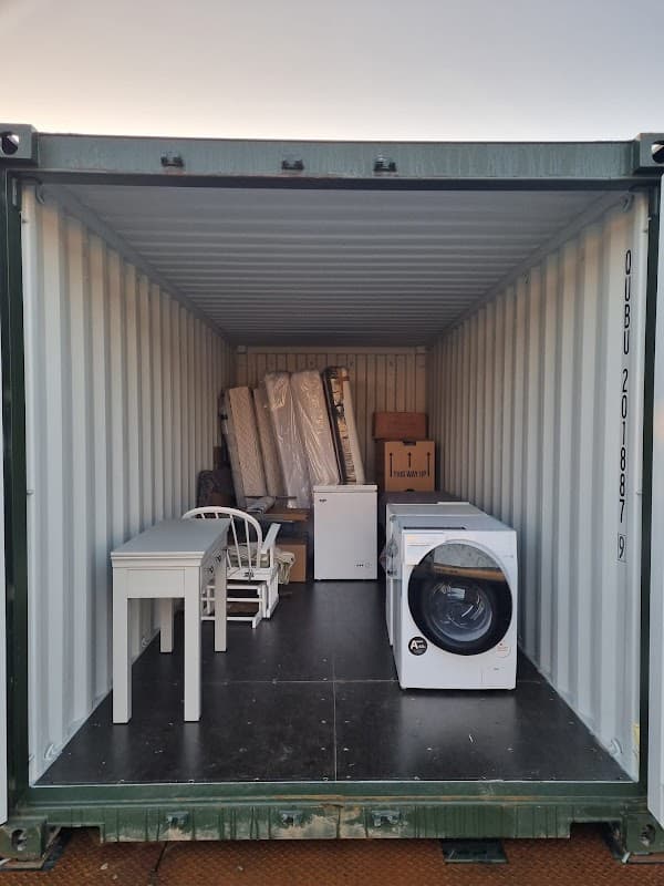 Storage container filled with furniture, a washing machine, and boxes in a neat arrangement.
