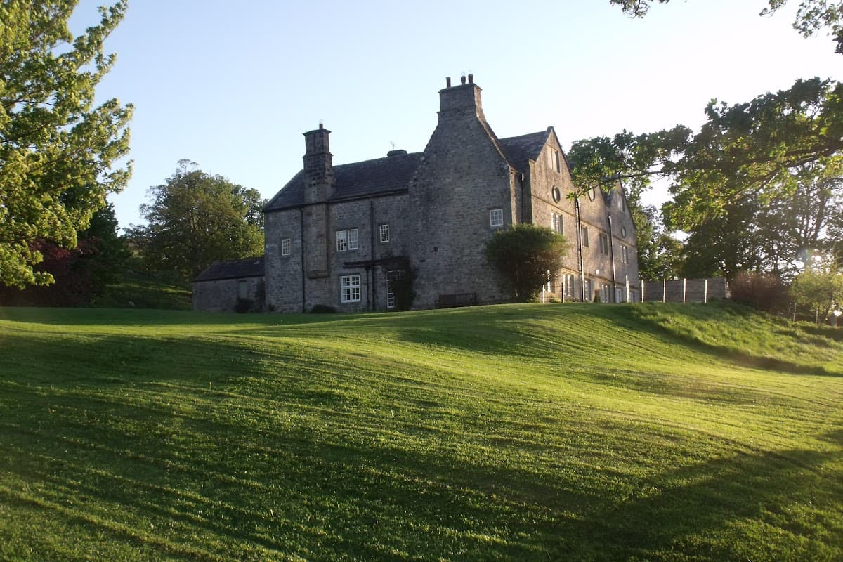 Braithwaite Hall Bed & Breakfast, a stone building surrounded by lush green lawns and trees in Coverham, Yorkshire.