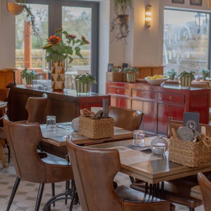 Cozy dining area with wooden tables, wicker baskets, and sunflowers, featuring red cabinets and greenery in a warm atmosphere.
