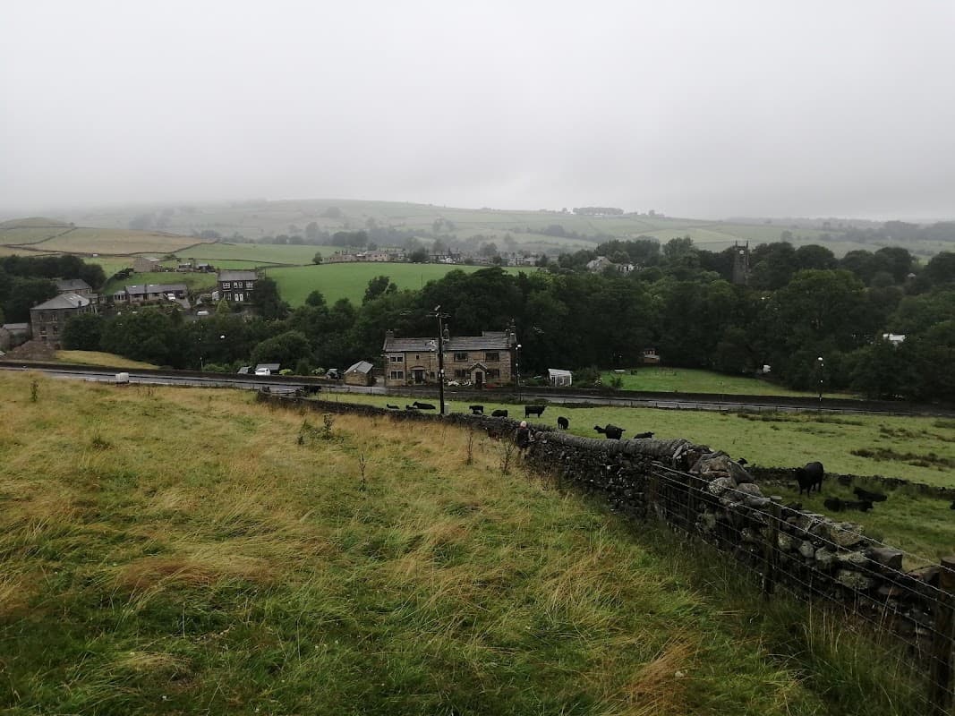 Rolling green hills under a cloudy sky, with a rustic barn and grazing cows in the foreground.