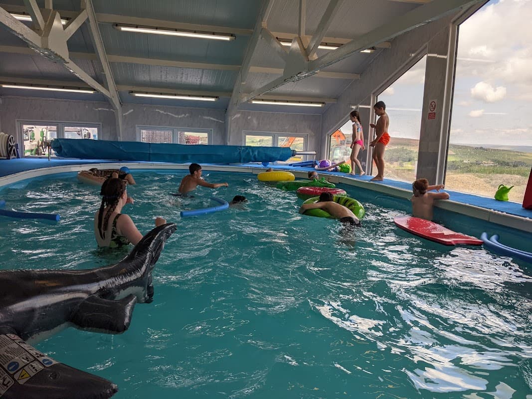 Indoor swimming pool at Ben's School of Swimming with children playing on floats and adults supervising.