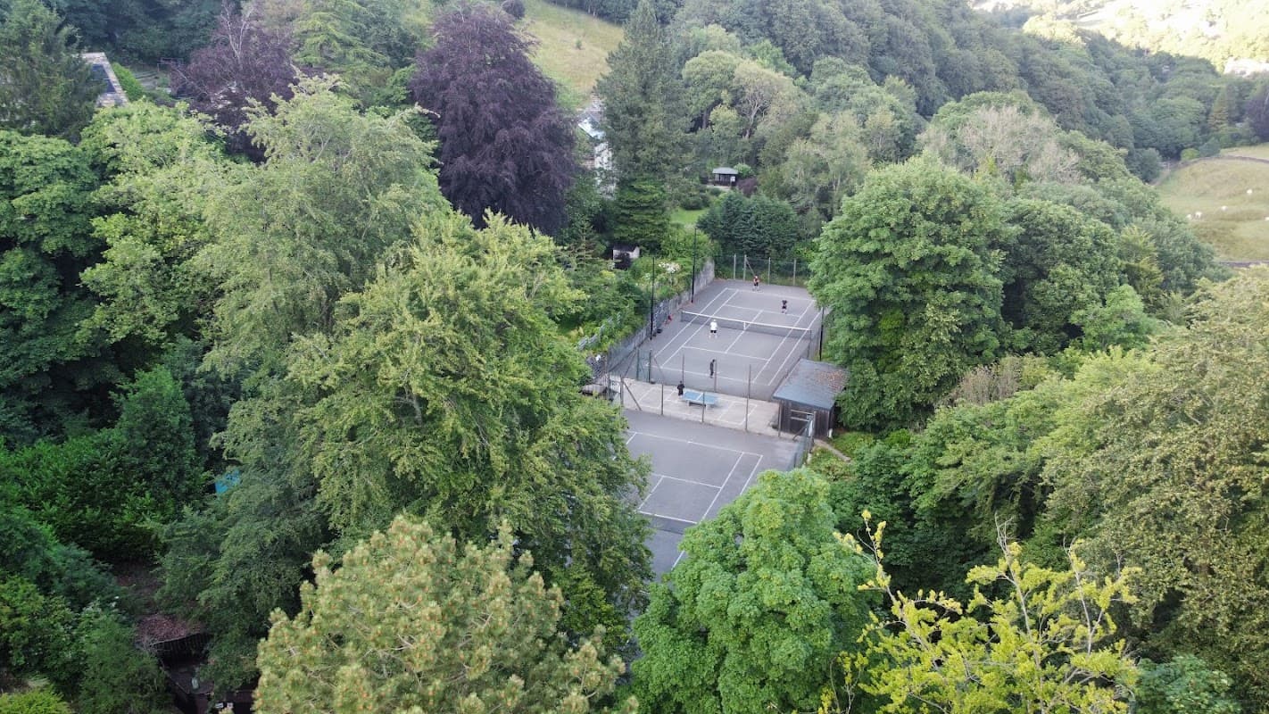 Tennis courts nestled among lush greenery in Cragg Vale, Yorkshire, with players visible on the courts.
