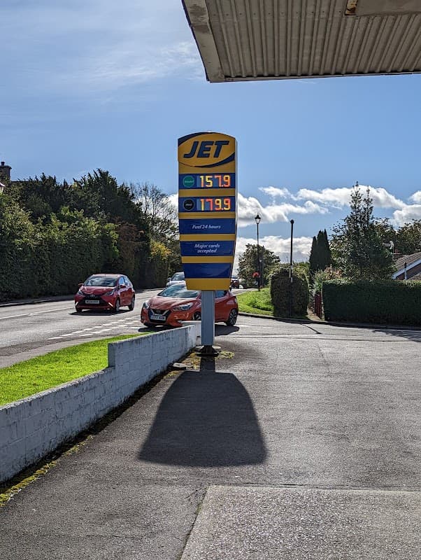 Crakehall Petrol Station sign displaying fuel prices, with cars parked nearby and greenery in the background.