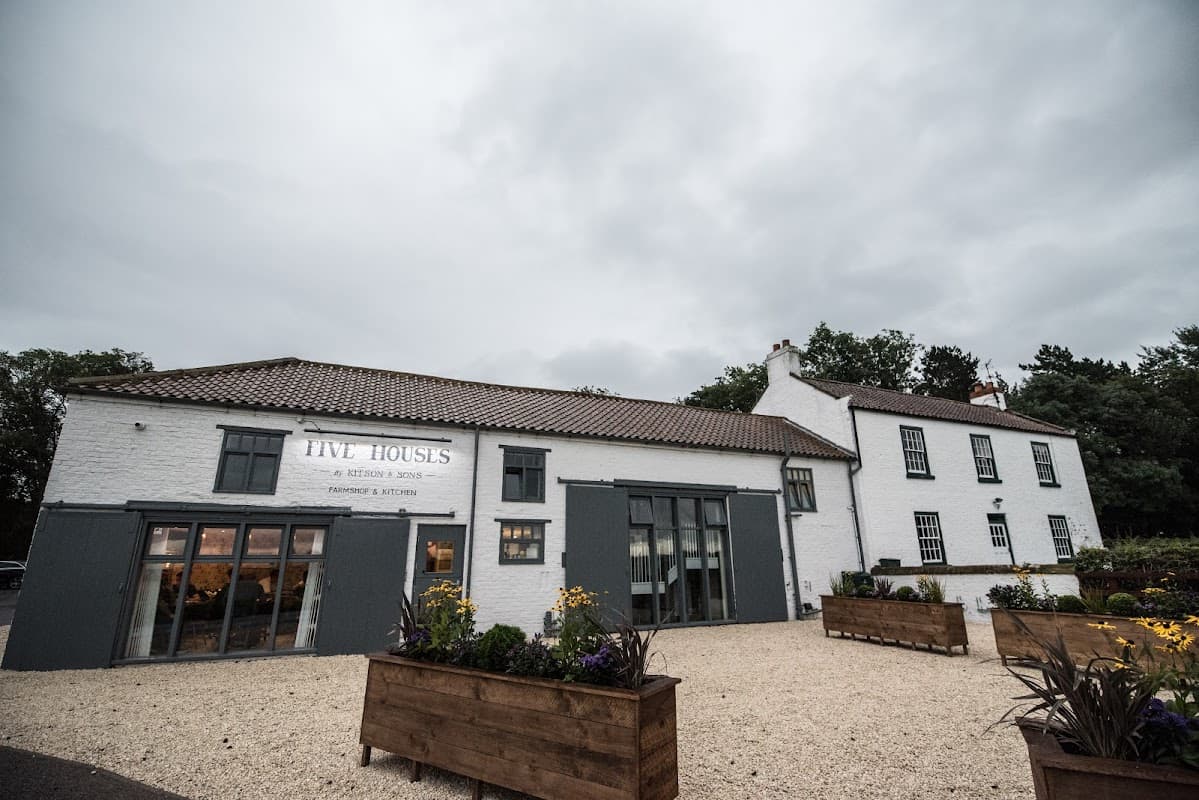 Five Houses Farm Shop & Kitchen, a charming café with a white exterior, large windows, and flower planters in Crathorne.