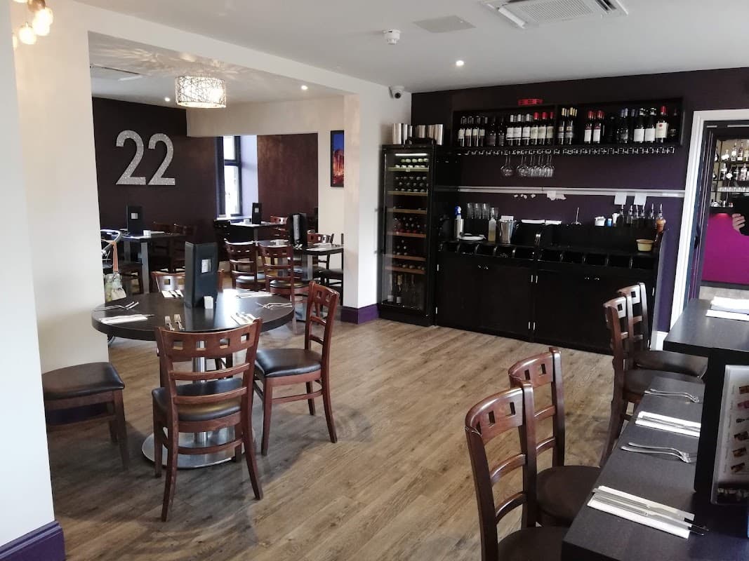 Modern dining area with wooden tables, chairs, wine rack, and purple accents, featuring the number 22 on the wall.
