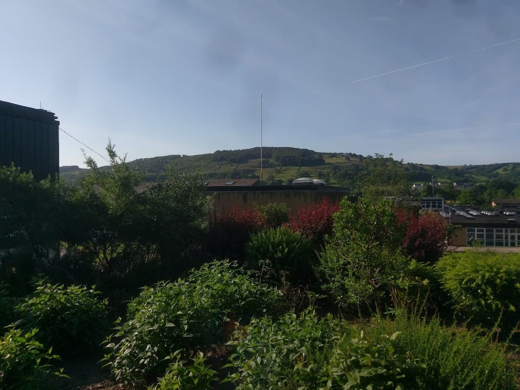 South Craven School surrounded by greenery, with rolling hills in the background under a clear blue sky.