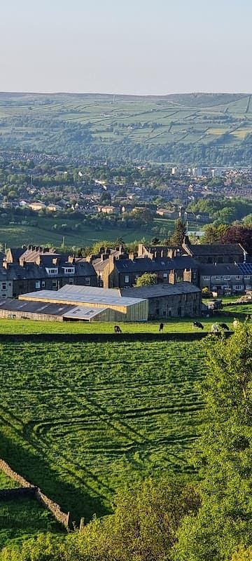 Cullingworth Village Hall surrounded by green fields and stone buildings, with hills in the background.