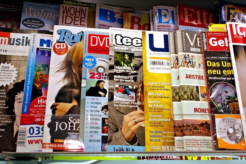 Magazines displayed on shelves, featuring various titles and colorful covers in a retail setting.