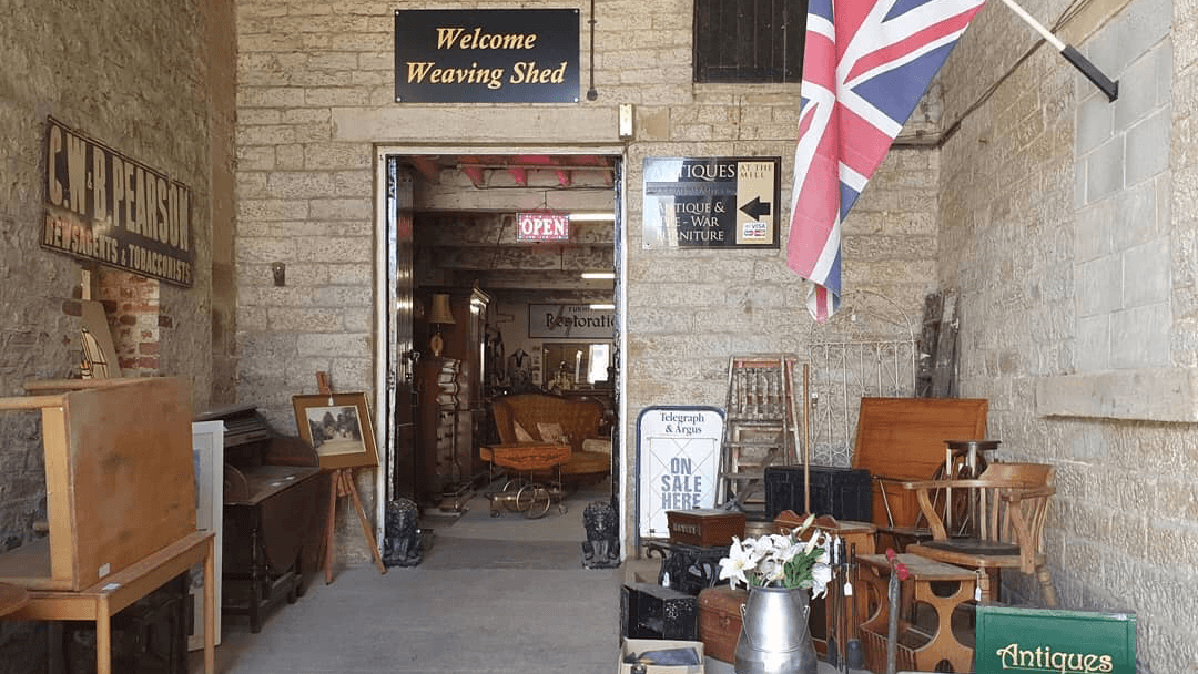Entrance to The Weaving Shed, featuring antiques, furniture, a British flag, and a welcoming sign.
