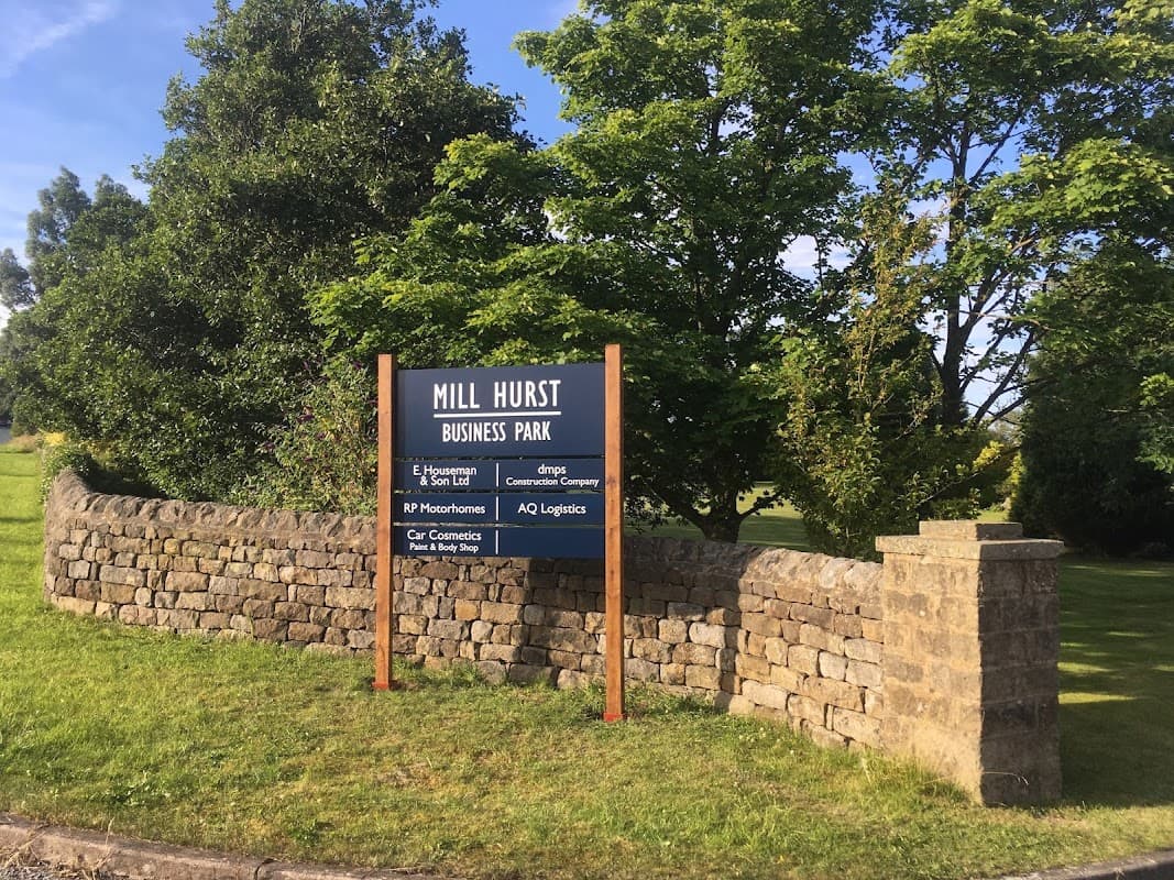 Sign for Mill Hurst Business Park surrounded by greenery and a stone wall in Dacre, North Yorkshire.