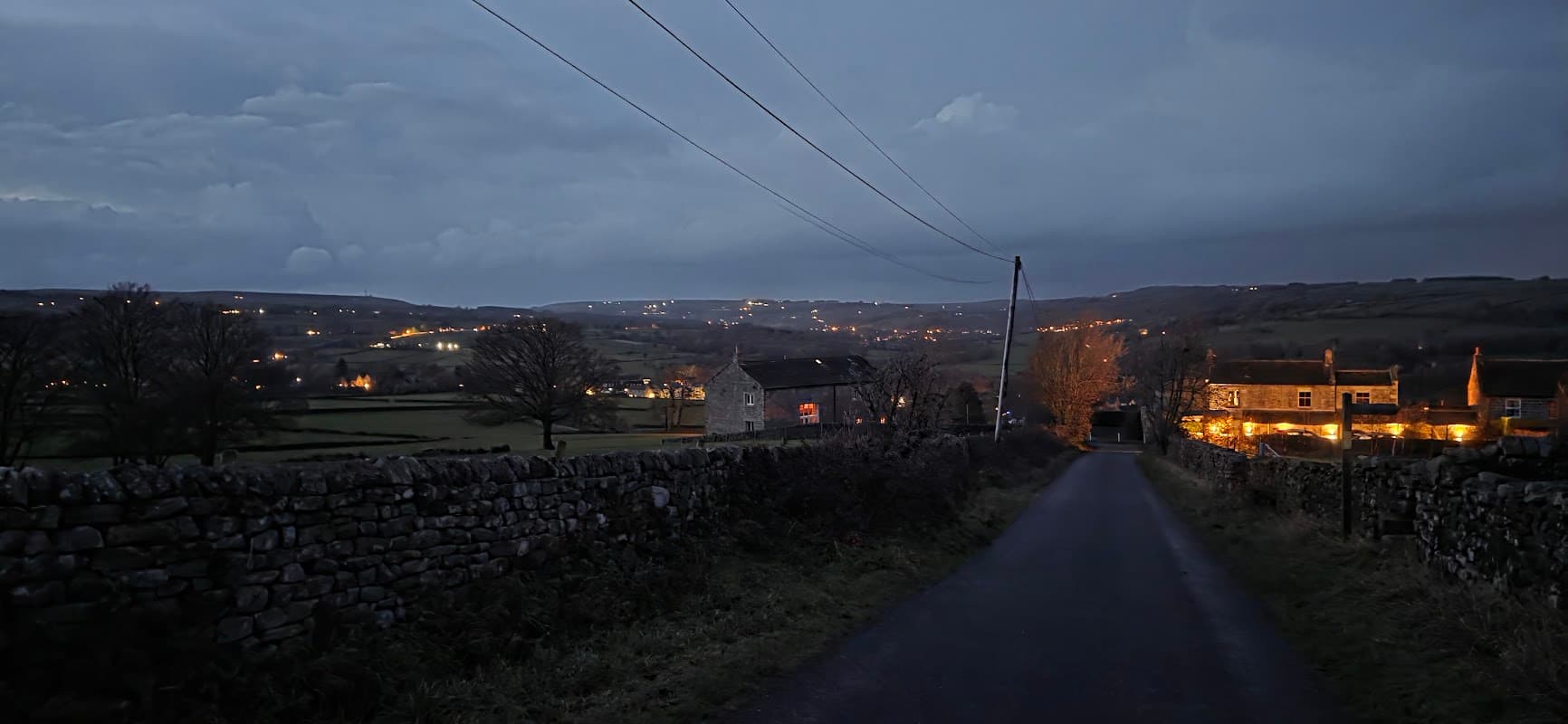 Darley Memorial Hall illuminated at dusk, surrounded by rural landscape and stone walls in North Yorkshire.