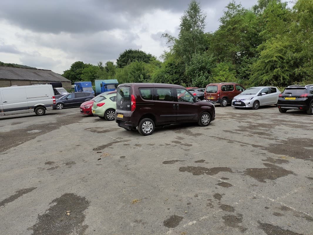 Cote Green Car Park in Deepcar, Yorkshire, with multiple parked cars and greenery in the background under cloudy skies.