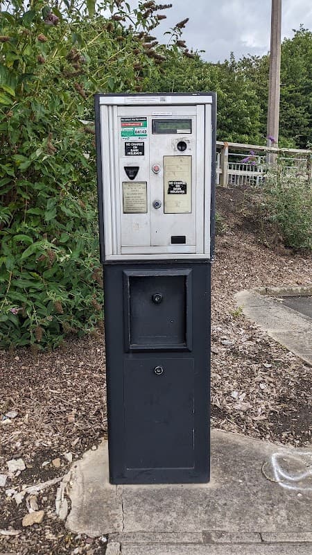 Parking meter with payment options, surrounded by greenery and gravel, in Wakefield Old Road Car Park, Dewsbury.