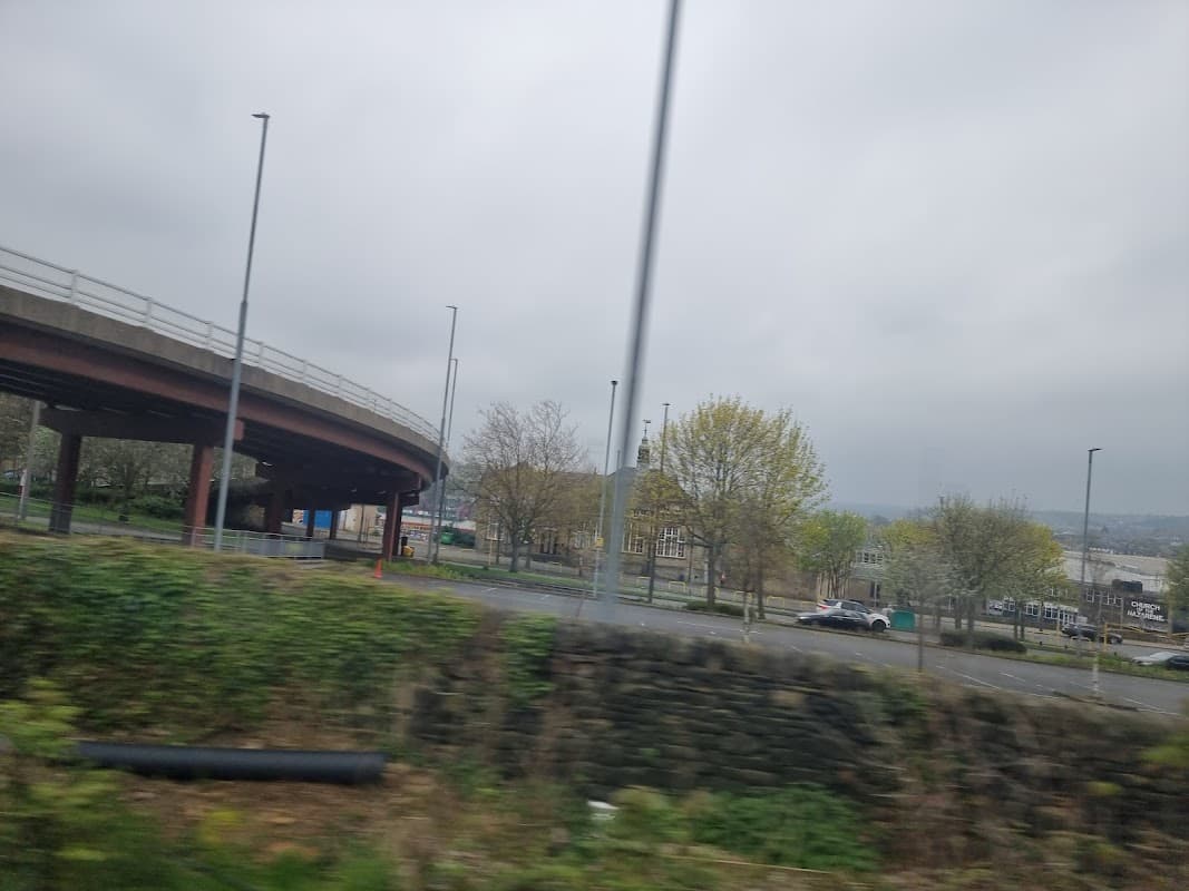 Wellington Road West Library with a Pay & Display area, surrounded by trees and a cloudy sky.