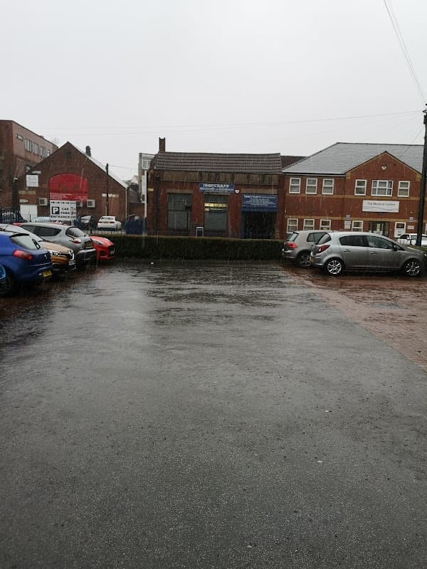 Pay & Display car park in Doncaster, wet pavement, parked cars, buildings in the background, overcast sky.