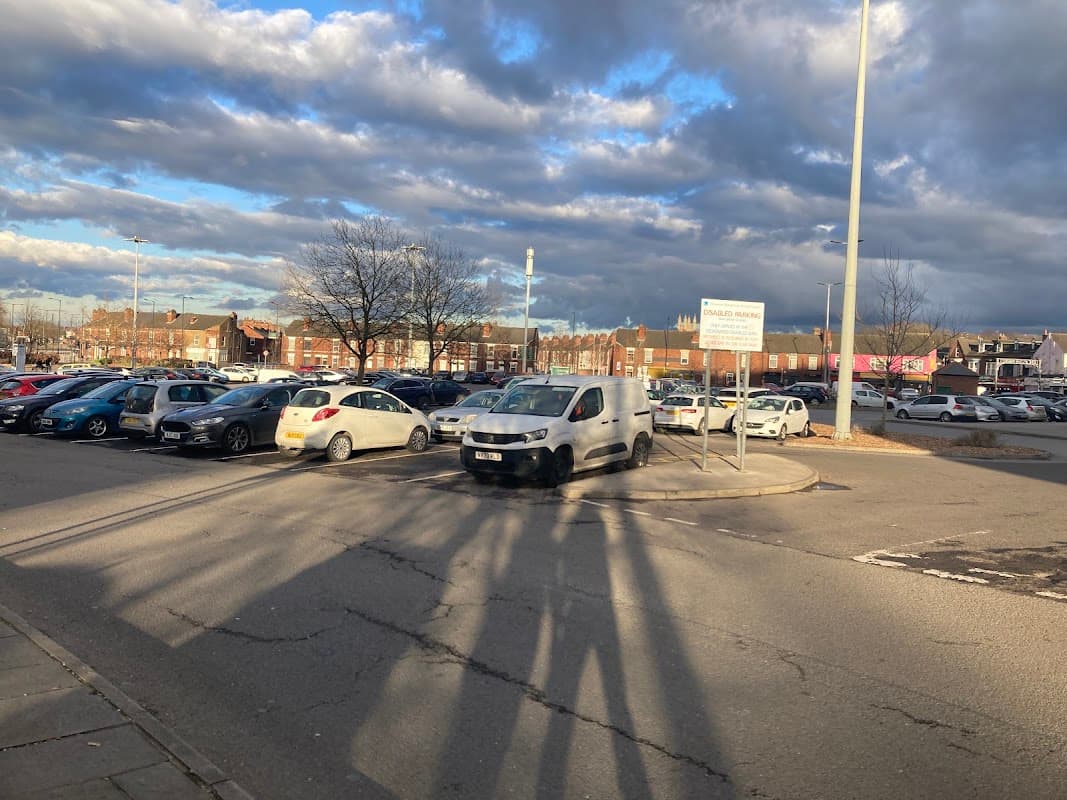 Car park with various vehicles, street lighting, and a cloudy sky in Doncaster, Yorkshire.