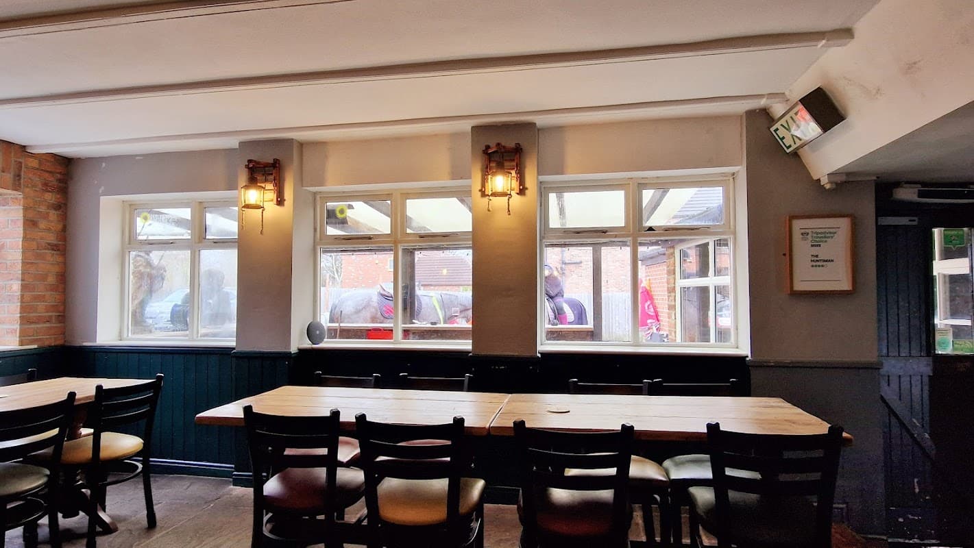 Interior view of The Huntsman restaurant with wooden tables, chairs, and large windows letting in natural light.