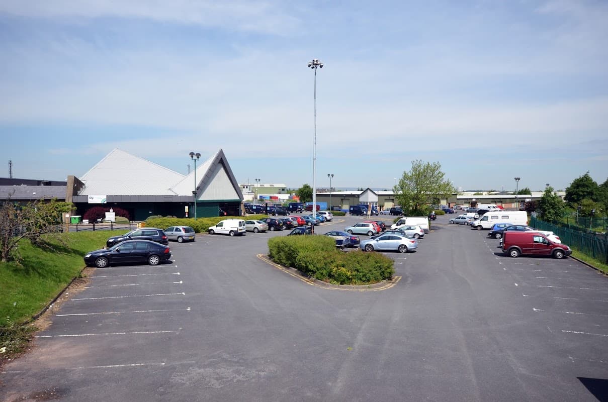 Self-storage facility in Dudley Hill with a spacious parking lot filled with various parked vehicles and greenery.