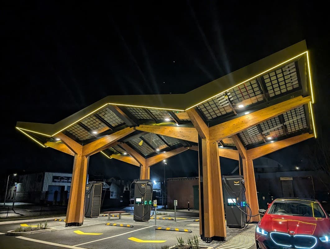Fastned Charging Station features a modern wooden structure with illuminated charging points and a parked electric car.
