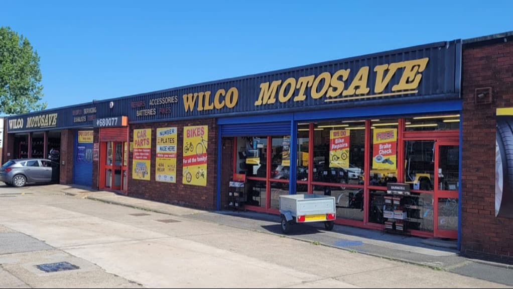 Exterior of Wilco Motosave shop with colorful signage, showcasing bikes, car parts, and accessories in Dudley Hill.