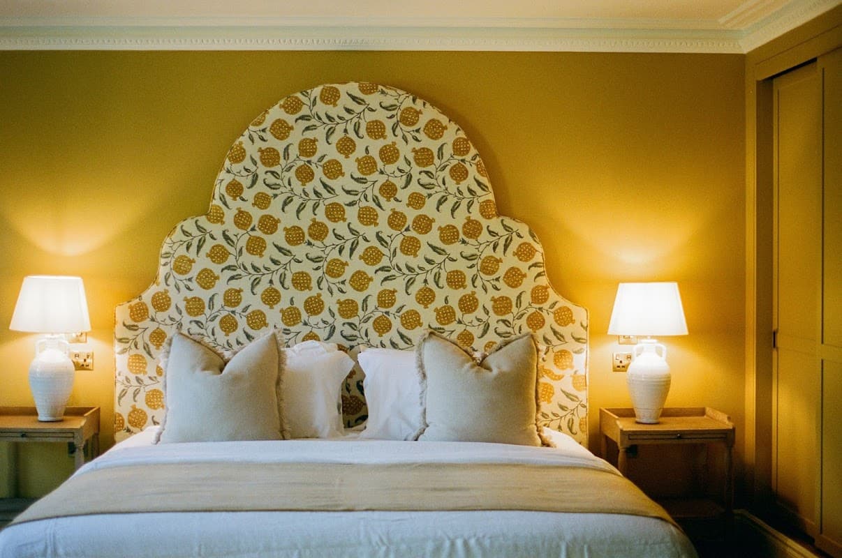 Elegant bedroom with a floral headboard, soft pillows, warm lighting, and stylish bedside tables.
