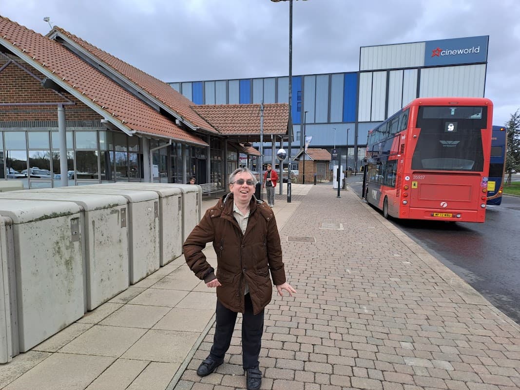 Monks Cross Park and Ride with a man in a brown coat, a red bus, and a Cineworld building in the background.
