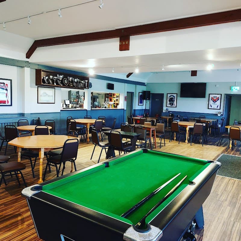 Interior of New Earswick Sports & Social Club featuring a pool table, tables, chairs, and trophies on display.