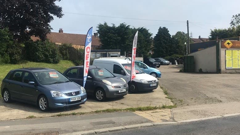 Easington Service Station with cars parked, "OPEN" flags, and a sign visible in the background.
