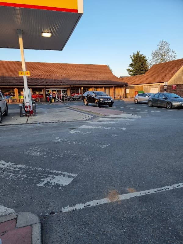 SPAR Manor Garage features a shop with a wooden facade, parked cars, and a clear blue sky above.