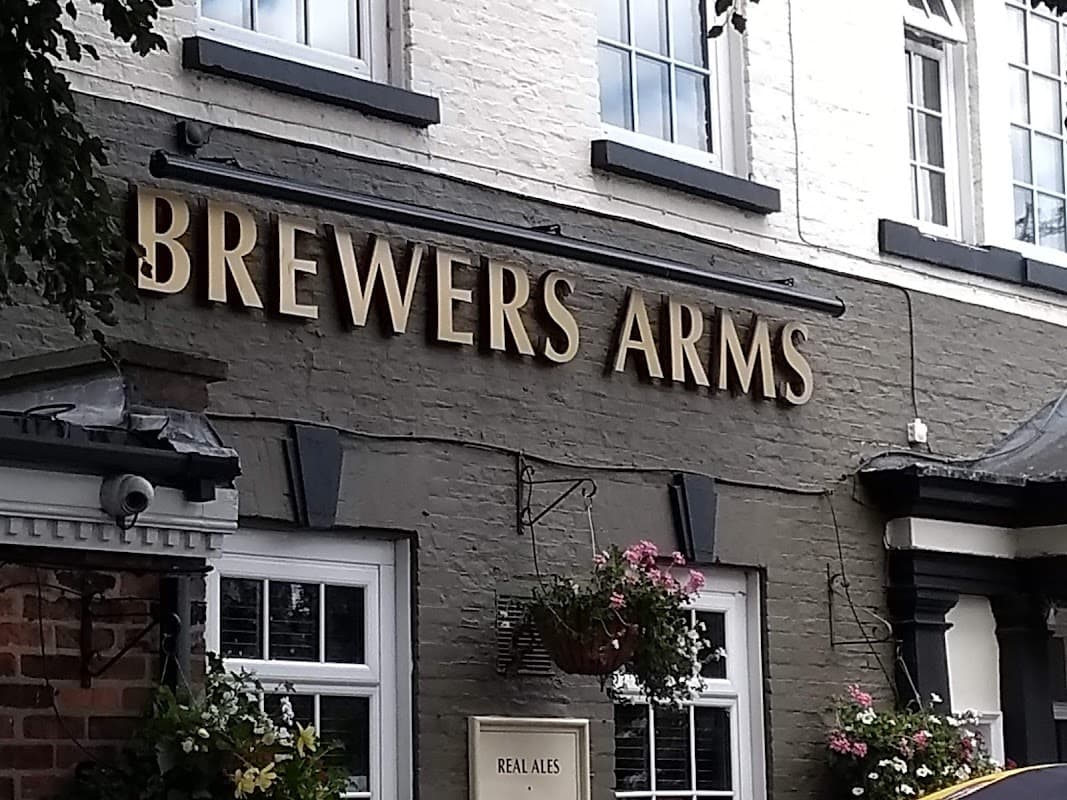 Signage for "Brewers Arms" bar, featuring flowers in hanging baskets and a welcoming entrance in East Cowick, Yorkshire.