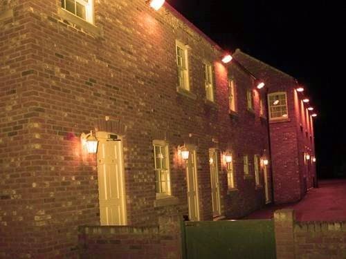 Brick building with multiple doors and warm lighting, set against a dark night sky in East Cowick, Yorkshire.