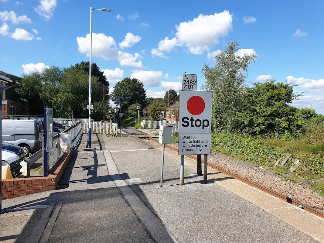 Railway station platform with a stop sign, tracks, and blue sky with clouds in East Cowick, Yorkshire.