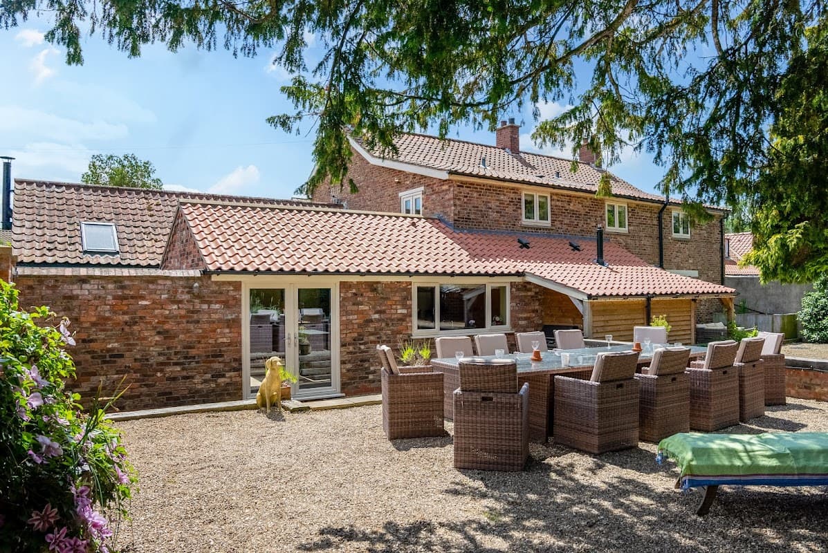 Spacious outdoor seating area with wicker chairs, a stone path, and a brick building under a clear blue sky.