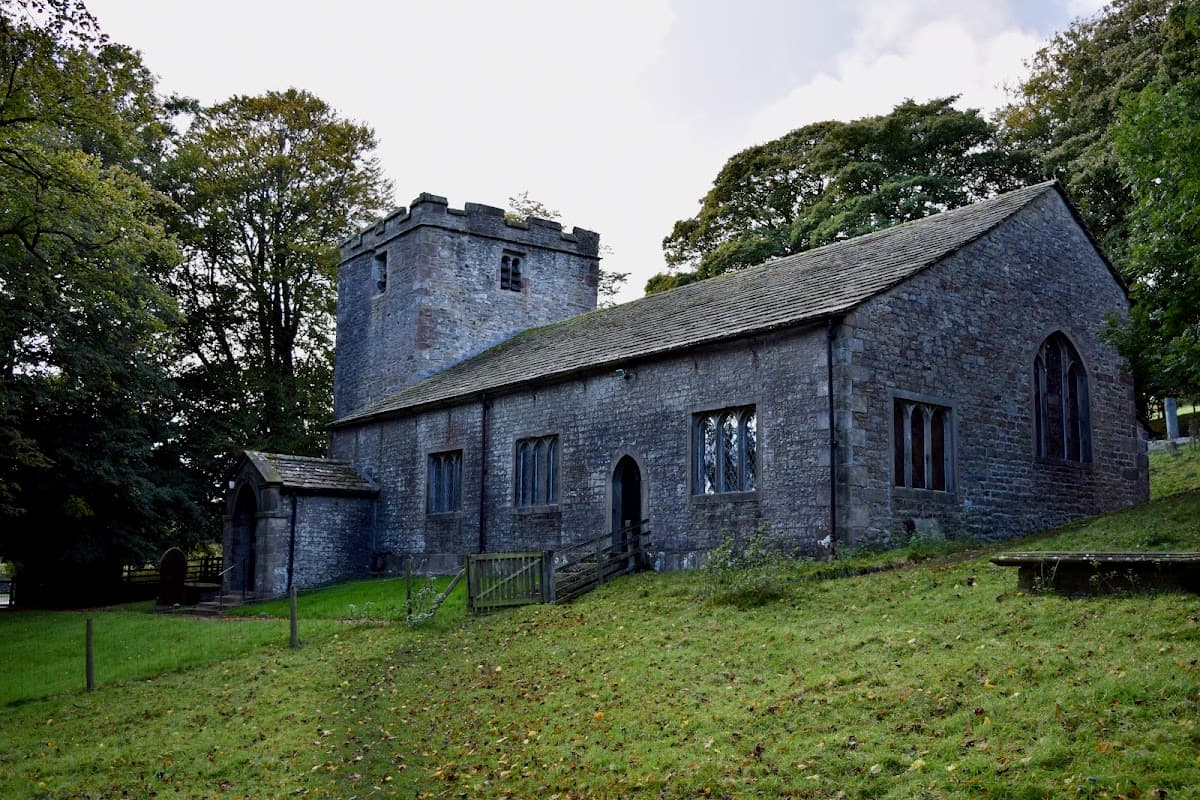 Stone church building with a tower, surrounded by trees and grassy grounds in East Marton, Yorkshire.