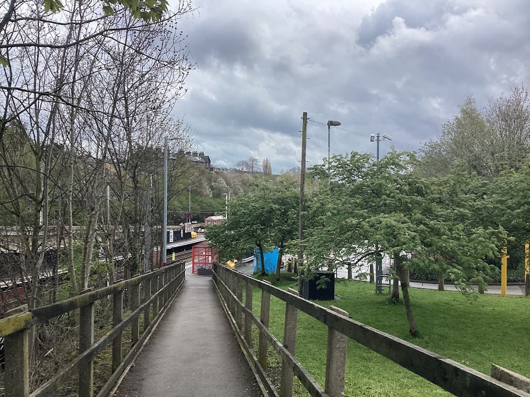 Pathway leading to bus stops, surrounded by trees and cloudy skies in East Morton, Yorkshire.