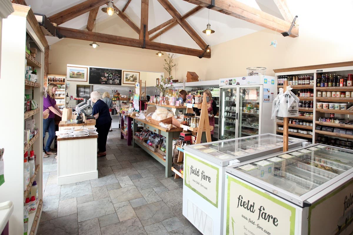 Bright shop interior with wooden beams, shelves filled with local products, and customers at the counter.