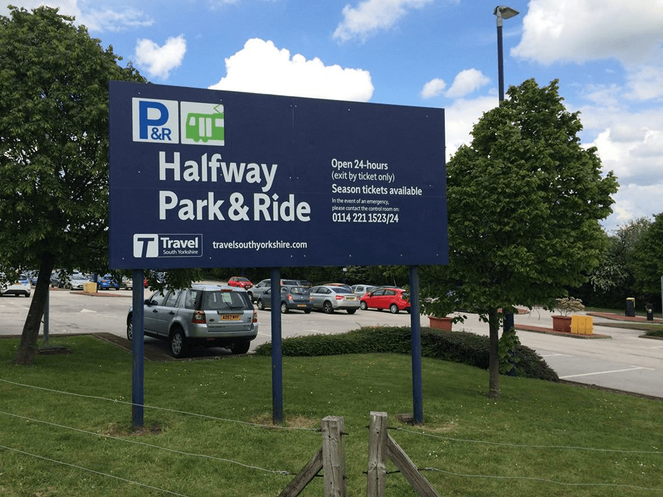Sign for Halfway Park & Ride in Eckington, Yorkshire, with parking area and trees under a partly cloudy sky.