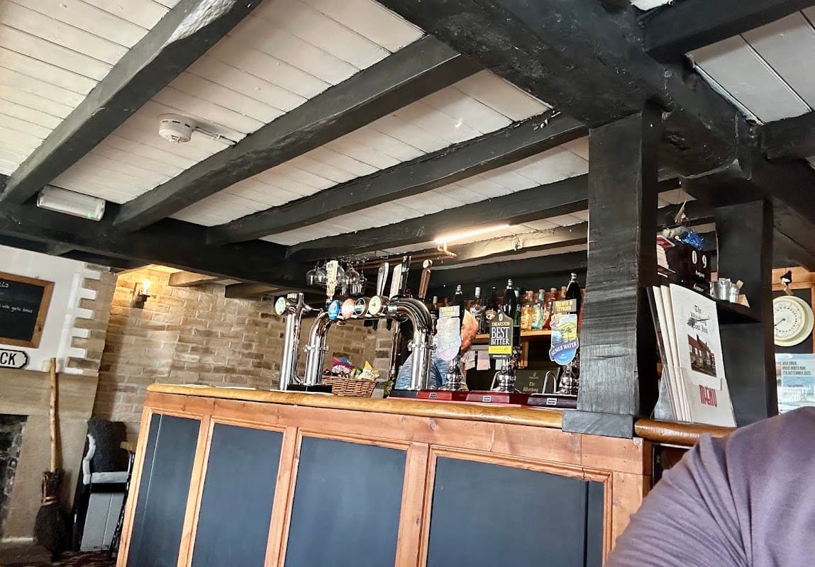 Interior view of the Witching Post Inn featuring a wooden bar, beer taps, and a cozy, rustic atmosphere.