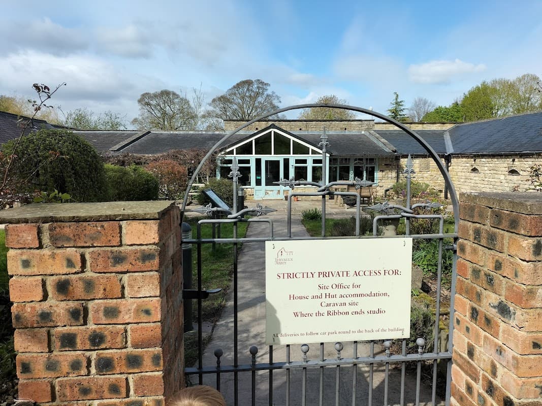 Gate with a sign reading "Strictly Private Access" leading to a courtyard with tables and chairs, surrounded by stone buildings.