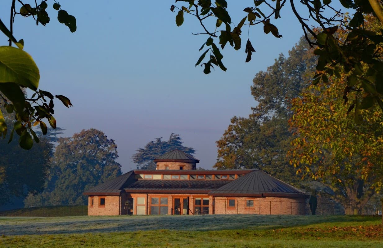 A modern brick building with a circular roof surrounded by trees and a frosty lawn in Escrick, Yorkshire.