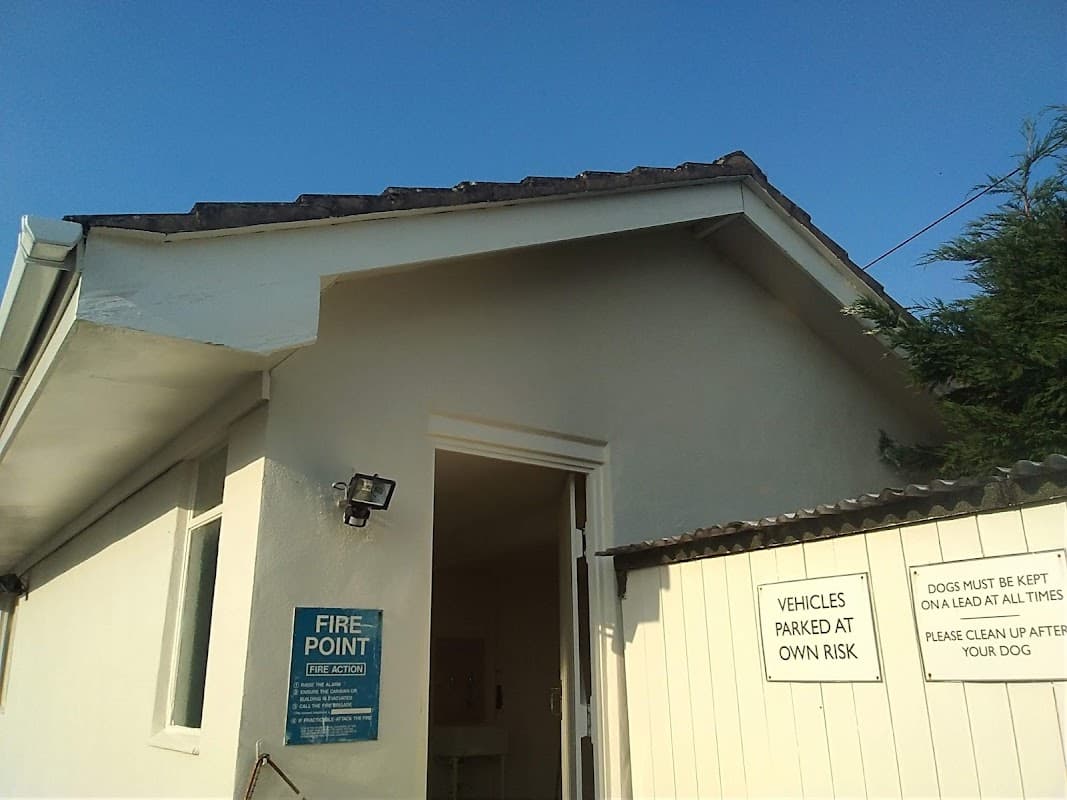 Exterior view of Dalesway Holiday Park featuring a fire point sign and notices about pets and vehicle parking.