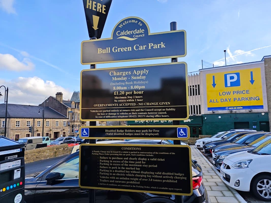 Welcome sign for Bull Green Car Park in Exley, Yorkshire, with parking charges and conditions displayed. Cars parked nearby.